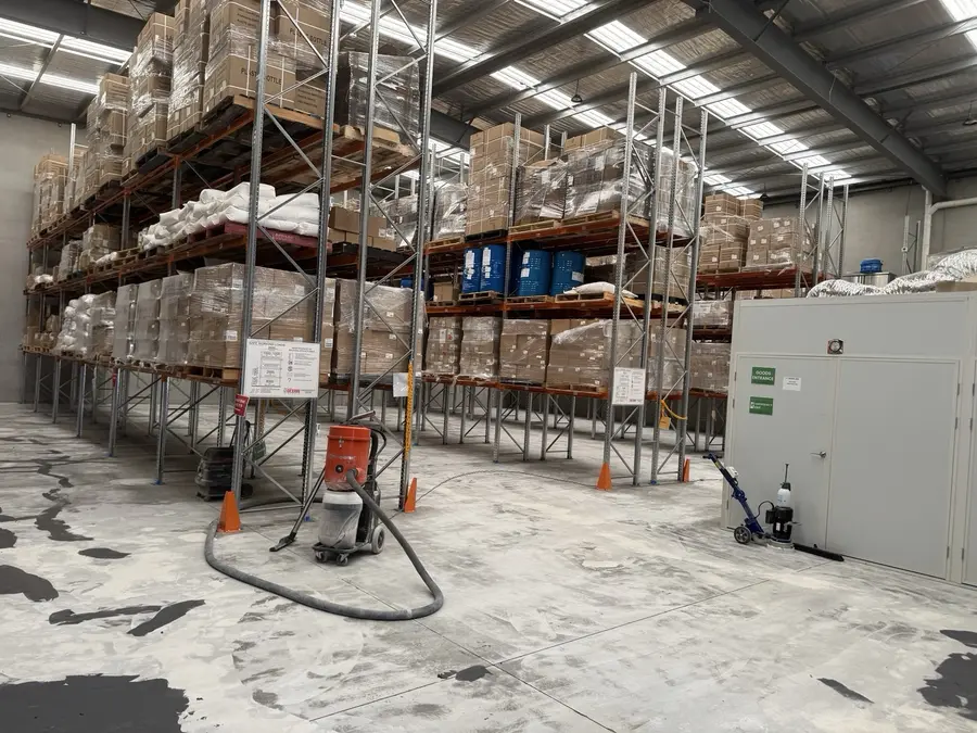 Warehouse floor during grinding and patch repairs around storage racks